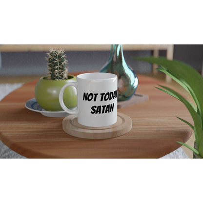 White ceramic mug with text 'Not Today Satan' on a table, 11oz microwave and dishwasher safe.