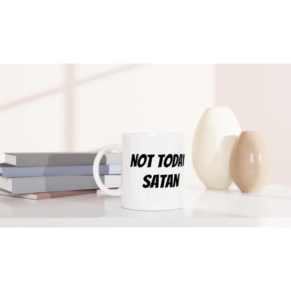 Today Satan White 11oz Ceramic Mug on table with vases and books, dishwasher and microwave safe.