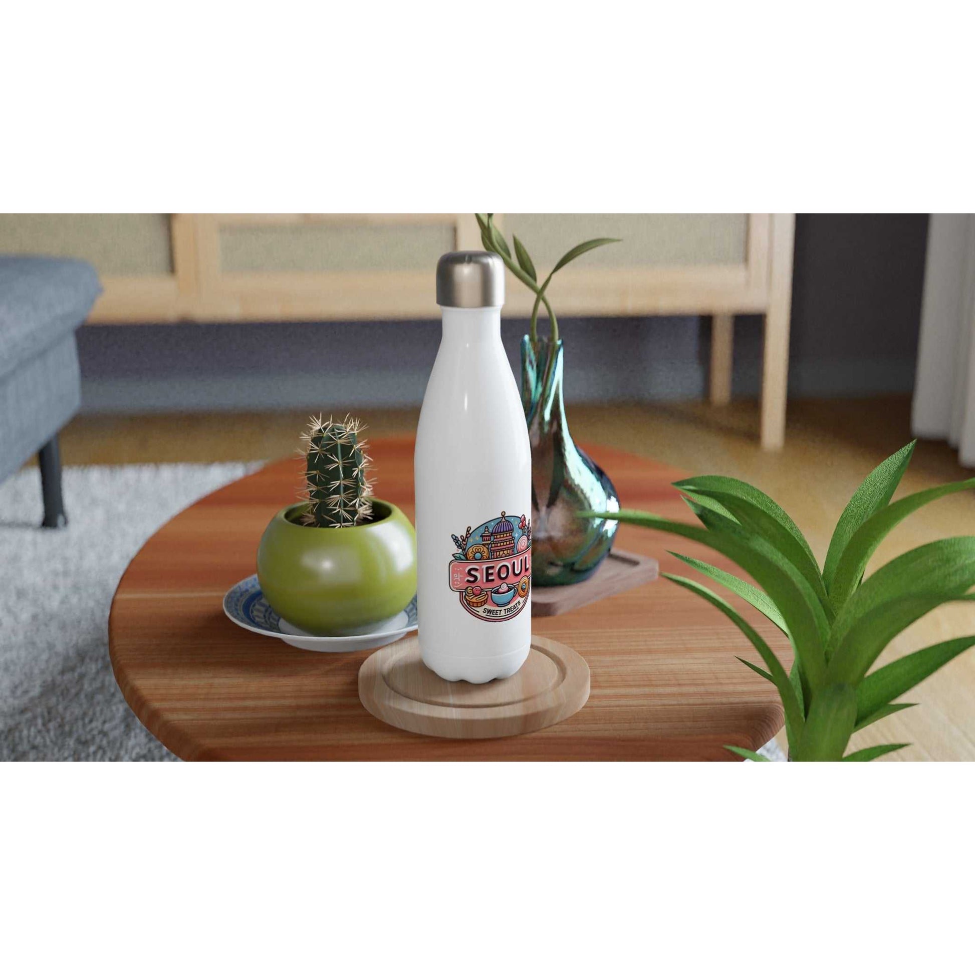 Seoul Sweet Treats Bakery Stainless Steel Water Bottle on a table with plants.