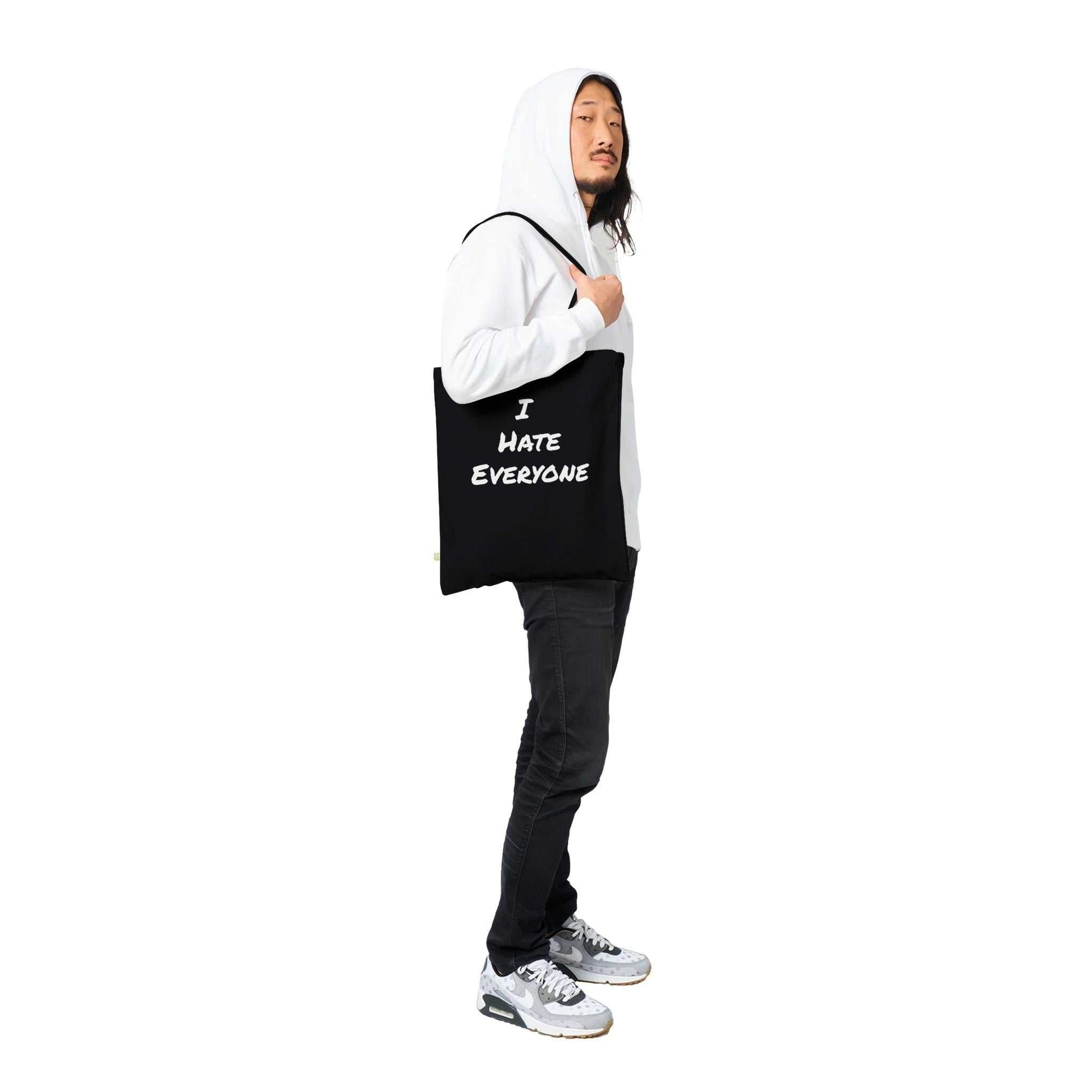 Man carrying a black tote bag with "I Hate Everyone" text, featuring reinforced stitching.