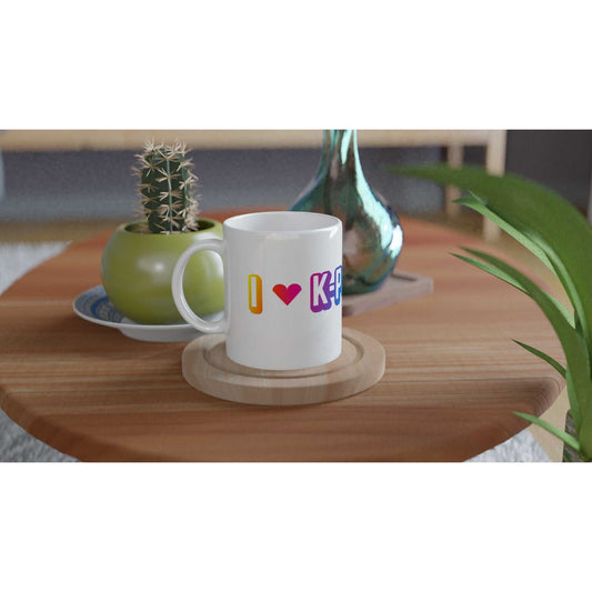 Love Kpop White 11oz Ceramic Mug on wooden table near plants.